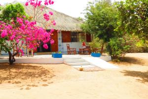 ein Haus mit rosa Blumen davor in der Unterkunft KASA HIBISCUS in Kafountine