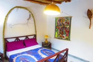 1 dormitorio con 1 cama y una pintura en la pared en KASA HIBISCUS, en Kafountine