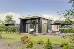 een zwart huis met een tuin en een patio bij Forest lodge with hot tub - 4 people in Rijssen