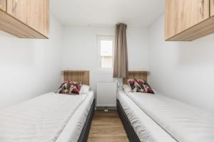 Duas camas num quarto com paredes brancas e uma janela em Forest lodge with hot tub - 4 people em Rijssen