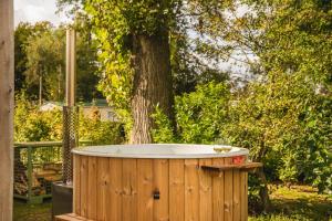 een houten bad naast een boom bij Forest lodge with hot tub - 4 people in Rijssen +1 foto