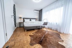 ein Schlafzimmer mit einem Bett und einem Holzboden in der Unterkunft City Apartments FN L 6 KLIMATISIERT mit Balkon - Deluxe Doppelzimmer in Friedrichshafen