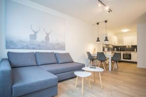a living room with a blue couch and a kitchen at Appartement - Weltringpark 2-T Winterberg in Winterberg