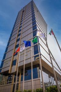 un edificio alto con banderas delante en Grand Villaggio Hotel Abu Dhabi, en Abu Dabi