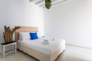 a white bedroom with a bed with blue pillows at Villa ANASA private Pool & Jacuzzi 8pax at Panormos in Mykonos