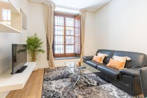 a living room with a black leather couch and a table at Angeles Santa Cruz Deluxe by Valcambre in Seville