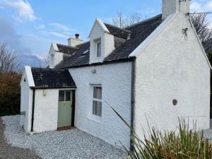 a white house with a green door on the side at Hawthorn Dene in Torrin