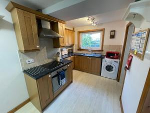 a kitchen with wooden cabinets and a washer and dryer at Hawthorn Dene in Torrin