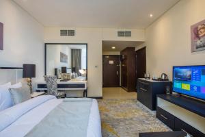 Cette chambre comprend un grand lit et une télévision. dans l'établissement Grand Villaggio Hotel Abu Dhabi, à Abu Dhabi