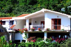 een wit huis met bloemen op het balkon bij Monten in Sveti Stefan
