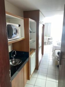a small kitchen with a sink and a microwave at Ponta Negra Flat ByHotéis in Natal
