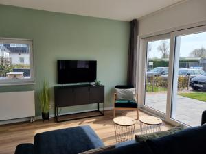 een woonkamer met een flatscreen-tv en een bank bij Vakantie vieren aan het Sneekermeer in Offingawier