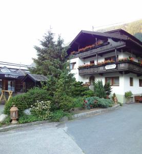 a large white building with a balcony and a tree at Bergsteiger-Zimmer Pension Obermair in Mayrhofen