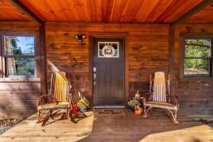 a front porch of a cabin with two chairs and a door at *NEW* Cozy mountain view cabin close to lake and hiking in Robbinsville