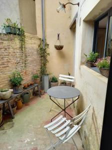 een tafel en stoelen op een patio met planten bij Au bois radieux - option massage in Bellême