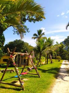 a swing set in a park with palm trees at Recanto dos Pássaros - Sana Chalés in Sana