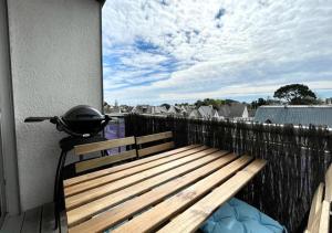 eine Holzbank auf einem Balkon mit Grill in der Unterkunft LE PADDAIR in Quiberon