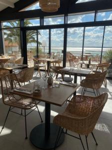 a restaurant with tables and chairs with a view of the ocean at Hôtel L'Albatros in Saint-Trojan-les-Bains