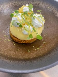 a plate with a doughnut with cream and greens on it at Hôtel L'Albatros in Saint-Trojan-les-Bains