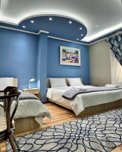 a bedroom with two beds and a blue wall at Vila A Hotel in Korçë