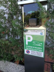 a parking meter with a sign on it next to a tree at Hotel Marconi in Padova