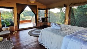 1 dormitorio con 1 cama en una habitación con ventanas en HBG Glamping community Yoga & Wellness space en Santa Teresa