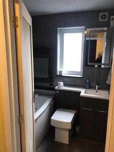 a bathroom with a toilet and a sink and a window at Double Room next to Burnham Elizabeth Line Station in Slough