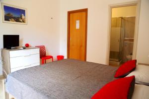a bedroom with a bed with red pillows and a television at B&B Siciliò in Santa Flavia