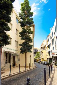 uma árvore numa rua de paralelepípedos ao lado de um edifício em Residencial Monaco em Funchal