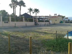 a parking lot with palm trees and a fence at Don Juan Beach Resort in Estepona