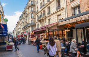 un grupo de personas caminando por una concurrida calle de la ciudad en 47m2 Calme au cœur de Parîs, en París
