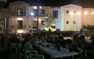 a group of people sitting at a table at night at Renia Hotel Agia Pelagia -Crete in Agia Pelagia