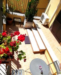 a patio with red flowers and a table and chairs at B&B Siciliò in Santa Flavia