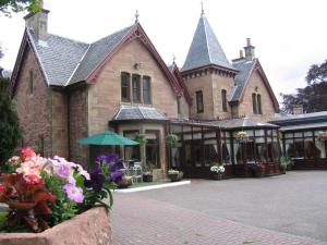 a large brick building with flowers in front of it at Craigmonie Hotel Inverness by Compass Hospitality in Inverness