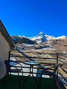 a table and two chairs on a balcony with snow covered mountains at Giorgi's Guest House in Kazbegi