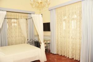 a bedroom with white curtains and a bed and a chandelier at Le scuderie di Villa Ravenna Luxury House in Sannicola