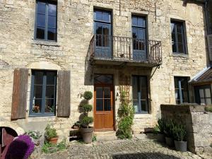 a stone building with a wooden door and a balcony at Maison Galimard in Flavigny-sur-Ozerain