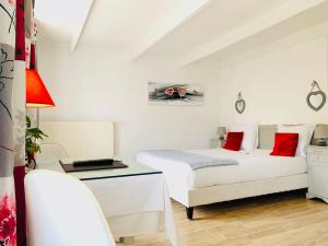 2 camas en una habitación blanca con almohadas rojas en Hôtel Restaurant La Désirade, en Saint-Désirat