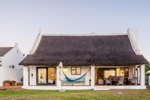a house with a thatched roof and a hammock at Silversands Beach Villa in St Helena Bay