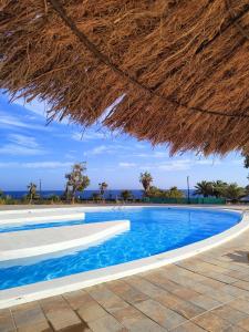 duży basen ze słomianym parasolem w obiekcie Ailana Suite Vistas al Mar y con Piscina w Costa Teguise