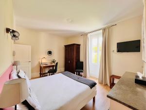 a bedroom with a bed and a desk and a television at Hôtel Restaurant La Désirade in Saint-Désirat