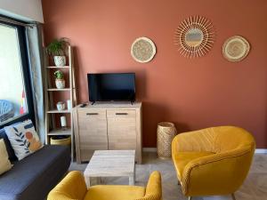 sala de estar con sofá y TV en Escapade Courseullaise, en Courseulles-sur-Mer