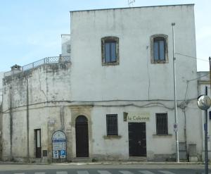 un vieux bâtiment blanc au coin d'une rue dans l'établissement Casa Marchese, à Salice Salentino