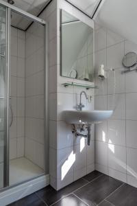 a bathroom with a sink, mirror, and bath tub at Hotel Hulsman in Valkenburg