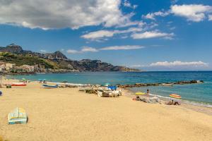 a beach with people sitting on the sand and the water at La Casa Di Stefe in Giardini Naxos
