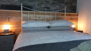 a bedroom with a white bed with a wooden headboard at Merrion Cottage Penmachno Betws y Coed Conwy in Penmachno