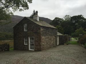 an old stone house sitting on a gravel driveway at Wood House Cottage in Cockermouth