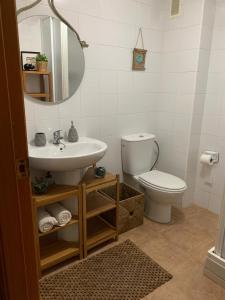 a bathroom with a sink and a toilet and a mirror at Apto con piscina en la playa cerca de VLC con AC in Puzol