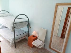 a bedroom with a bunk bed and a chair and a mirror at Casa Salamanca in Benidorm
