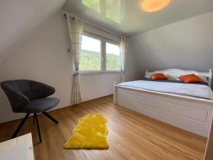 een slaapkamer met een bed, een stoel en een raam bij Haus Adler - Komplettes Ferienhaus am Badesee in Erzgrube